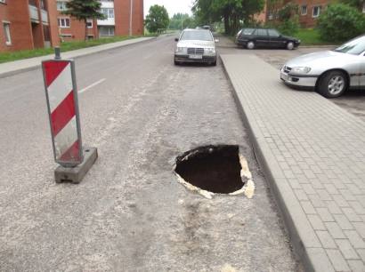 Apie atsivėrusią smegduobę vairuotojus įspėja kelio ženklas. Autoriaus nuotr.