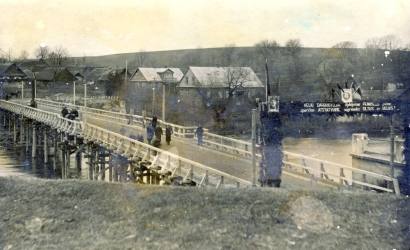 Apskrities centras Anykščiai apie 1947 m.: su laikinuoju mediniu tiltu per Šventąją ir su skardiniais bei šiaudiniais Ažupiečių stogais. A. Baranausko ir A. Vienuolio-Žukausko memorialinio muziejaus fondų nuotrauka.