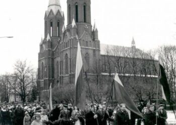 Pirmoji XX a. pabaigos anykštėnų Vasario 16-osios eisena 1989 m. Ją veda vienas iš Lietuvos Atgimimo šauklių anykštėnas Eligijus Smetona (centre tarp vėliavų). A. Baranausko ir A. Vienuolio-Žukausko memorialinio muziejaus fondų nuotrauka.