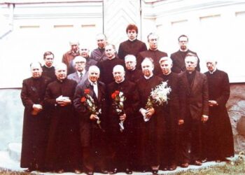 Bičiuliai kunigai 1989-aisiais sveikina E. Simašką (centre su rožių puokšte) su 80-mečiu. Tarp kunigų galinėje eilėje antras iš kairės stovi ir tuometinis Taujėnų klebonas, iš Kurklių parapijos kilęs Jonas Voveris. Dabar jau jis, pradėjęs antrą šimtmetį, yra pripažintas seniausiu Lietuvos dvasininku. Kun. Stepono Galvydžio (stovi už E. Simaškos) fotoalbumo nuotrauka iš A. Baranausko ir A. Vienuolio-Žukausko memorialinio muziejaus rinkinių.