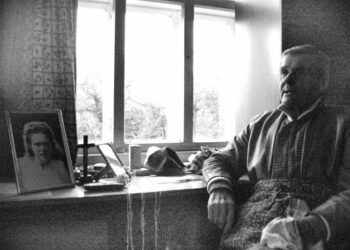 Ankstyvoje pavasario vakaro prieblandoje, atsirėmęs į stalelį su kryžiumi ir jau mirusios žmonos Bronės vestuvine nuotrauka, susimąstęs išmintingasis mokovas Bronius Neniškis.Autoriaus nuotr.