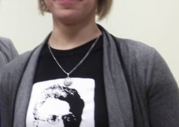 Aistė Kučinskienė smagiai šypsosi – pasipuošusi Lietuvių kalbos ir literatūros instituto platinamais originaliais atributais – marškinėliais su Vaižganto atvaizdu ir citata: „Eikš ant blaivinančio pašnekesio“.