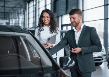 In good mood. Female customer and modern stylish bearded businessman in the automobile saloon.