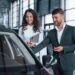 In good mood. Female customer and modern stylish bearded businessman in the automobile saloon.